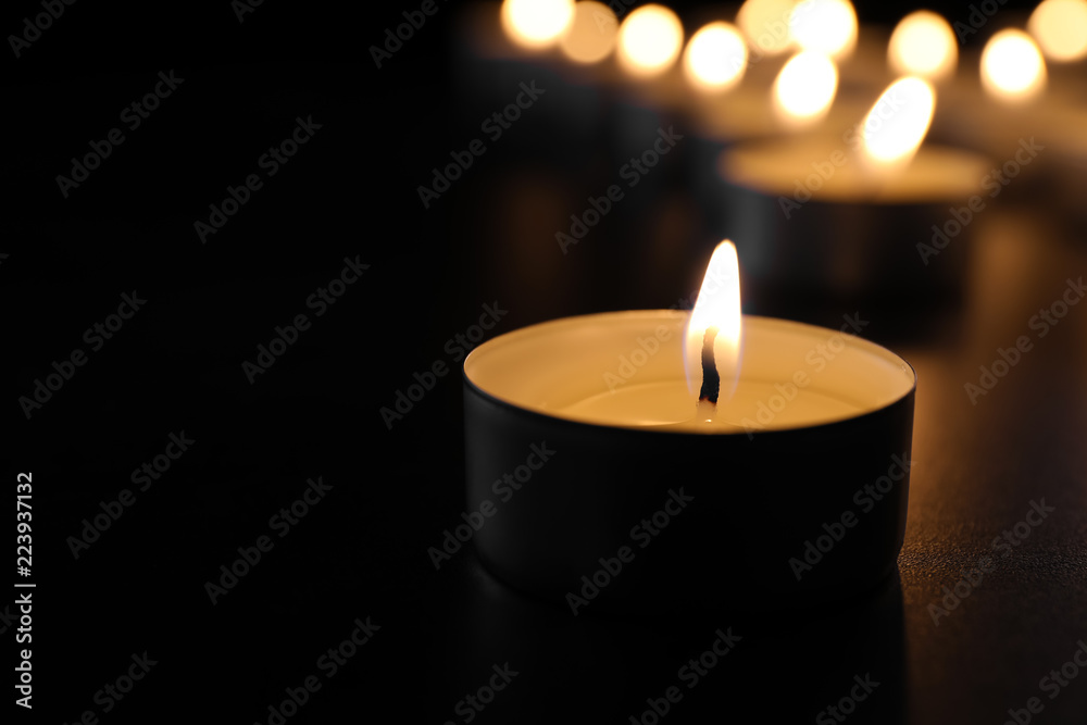 Burning candle on table in darkness, closeup with space for text. Funeral symbol Burning candle on table in darkness, closeup with space for text. Funeral symbol