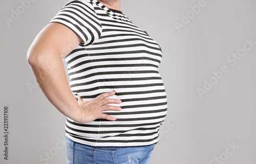 Fat woman on grey background, space for text. Weight loss