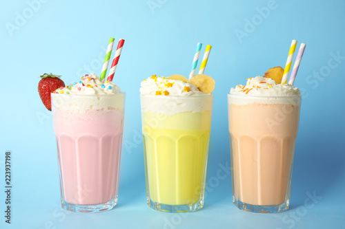 Glasses of tasty milk shakes on color background