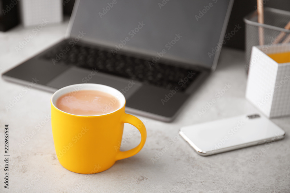 Yellow cup with coffee and phone near laptop on office table. Break time Yellow cup with coffee and phone near laptop on office table. Break time