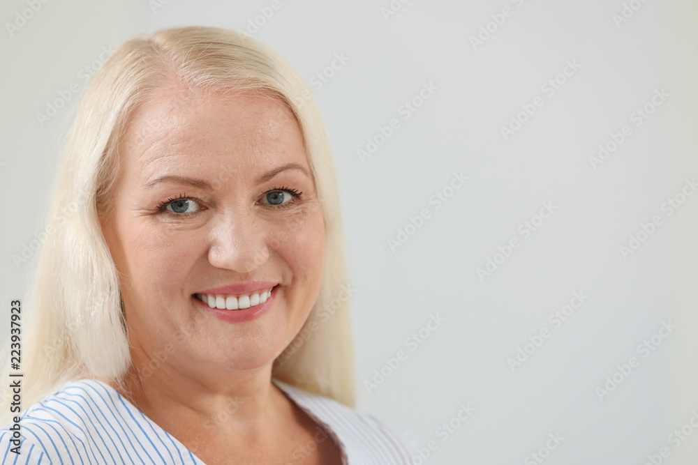 Portrait of beautiful older woman against light background with space for text Portrait of beautiful older woman against light background with space for text