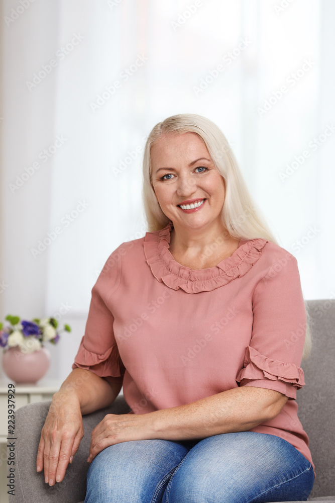 Portrait of beautiful older woman sitting on sofa indoors Portrait of beautiful older woman sitting on sofa indoors