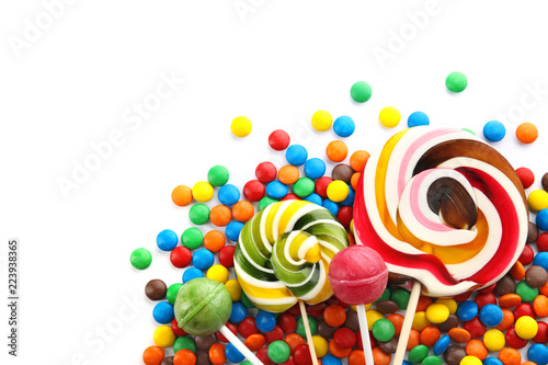 Lollipops and colorful candies on white background, top view