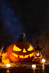 Carved pumpkin or jack-o-lantern in dark barn, Halloween holiday celebration concept