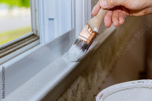 Fototapeta Naklejka Na Ścianę i Meble -  Close up of man hand carefully painting the edge of an house window