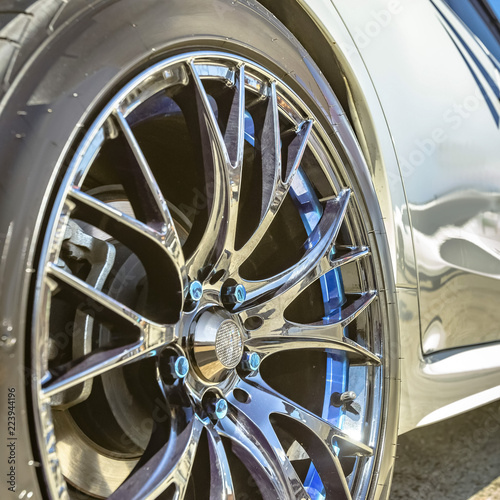 Silver tire rim with blue bolts of a white car photo