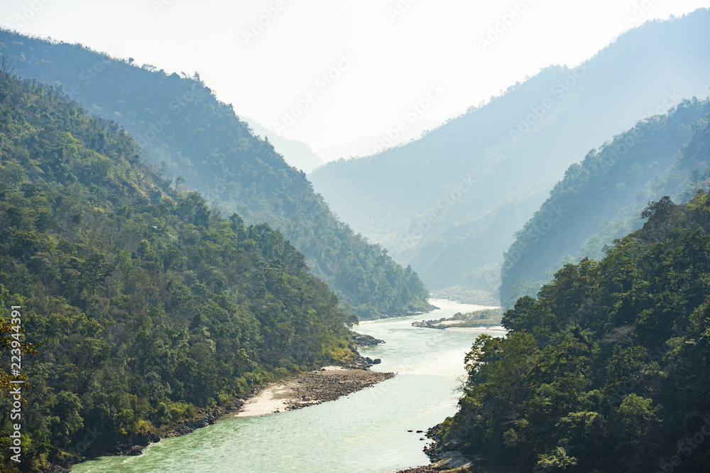 Spectacular view of the sacred Ganges river flowing through the green mountains of Rishikesh, Uttarakhand, India.