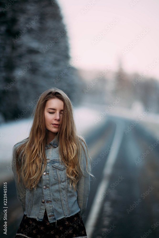 girl blonde in winter dress in snowy forest walking. frosty sunny morning in nature.