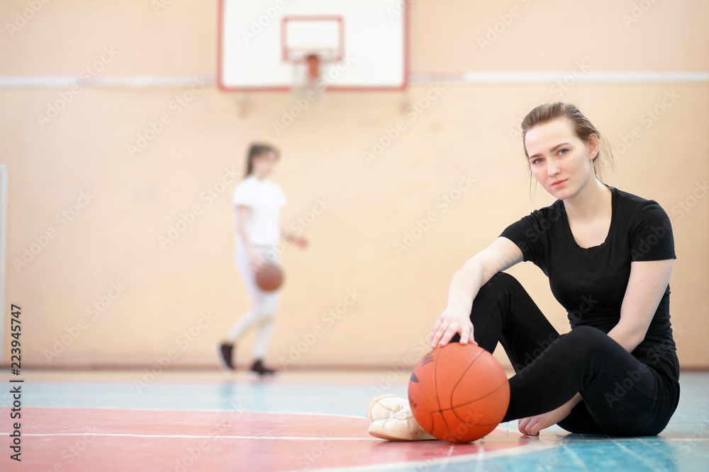 Naklejka premium Girl in the gym playing a basketball