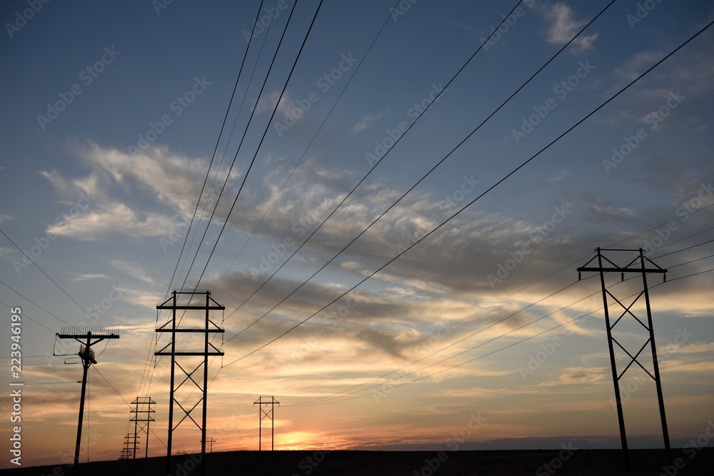 Sunset silhouette, rows of electrical power poles, high voltage power lines in Wyoming, USA