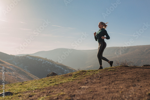Young fit woman running on a mountain top