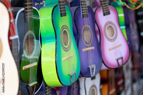 Rows of colorful practice guitars for kids hanging on the wall of a street vendor.