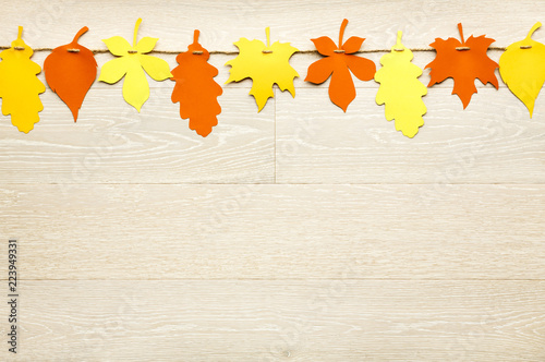 Simple, rustic country style Fall Thanksgiving decorations garland banner of colorful cut paper leaves on whitewashed wood background