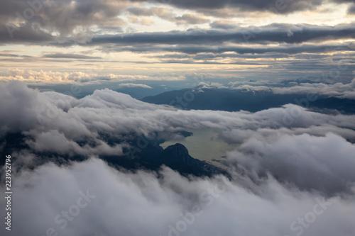 Beautiful aerial view of Howe Sound and Squamish covered in clouds during a cloudy summer sunset. Taken North of Vancouver, BC, Canada.a