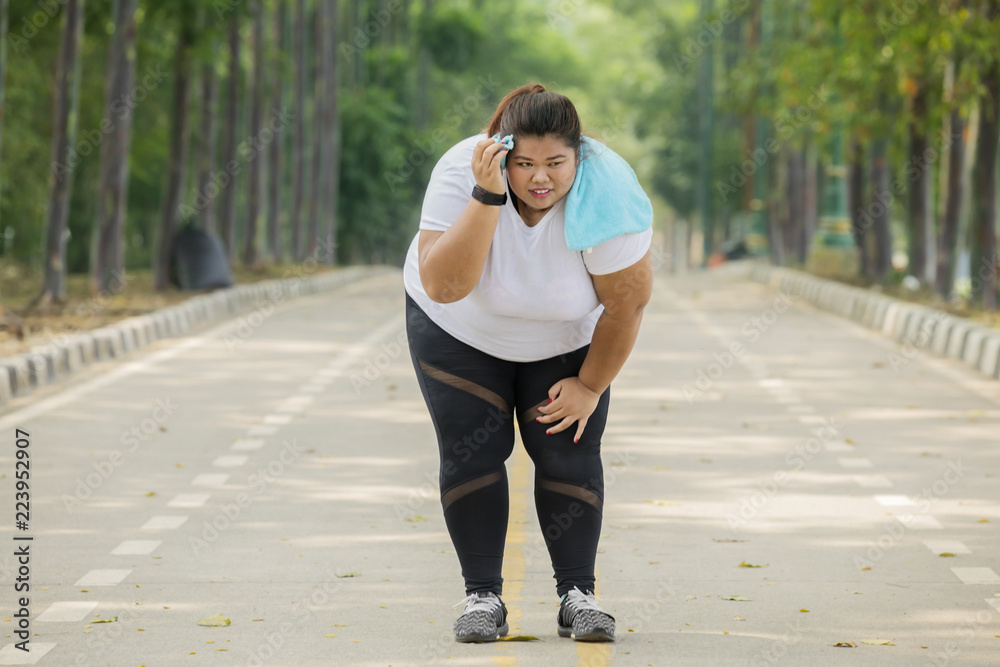 Obese woman looks tired after running