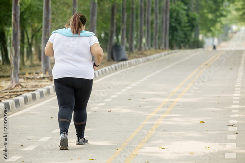 Overweight woman jogging on the road
