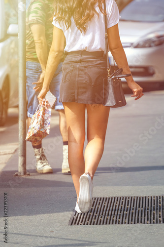 Beautiful girl wearing black mini dress and walking on Milan city street