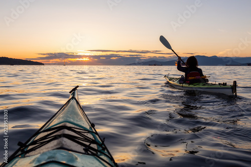 Girl Sea Kayaking during a vibrant sunny summer sunset. Taken in Vancouver, BC, Canada.