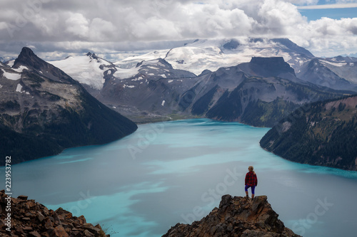 Woman standing on top of the Mountain overlooking a beautiful glacier lake. Taken on Panorama Ridge, Garibaldi, Near Whister, BC, Canada.