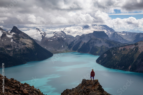 Woman standing on top of the Mountain overlooking a beautiful glacier lake. Taken on Panorama Ridge, Garibaldi, Near Whister, BC, Canada.