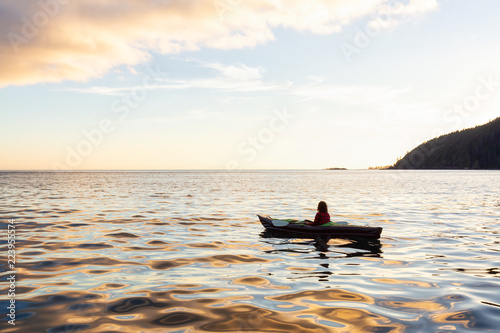 Girl kayaking in the Pacific Ocean during a cloudy summer sunset. Taken in San Josef Bay, Cape Scott, Northern Vancouver Island, BC, Canada.