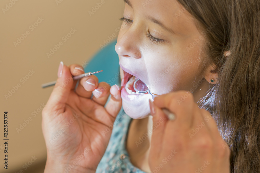 Little girl at the reception in the dentist's office. little girl sitting in a chair near a dentist after dental treatment. Little girl sitts in the dentist's office Little girl at the reception in the dentist's office. little girl sitting in a chair near a dentist after dental treatment. Little girl sitts in the dentist's office