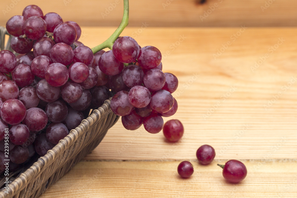 Close up of red grapes in a basket on a wooden background. Close up of red grapes in a basket on a wooden background.