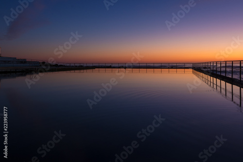 Dawn sky reflection in a seaside coastal pool. Early morning  twilight colours.