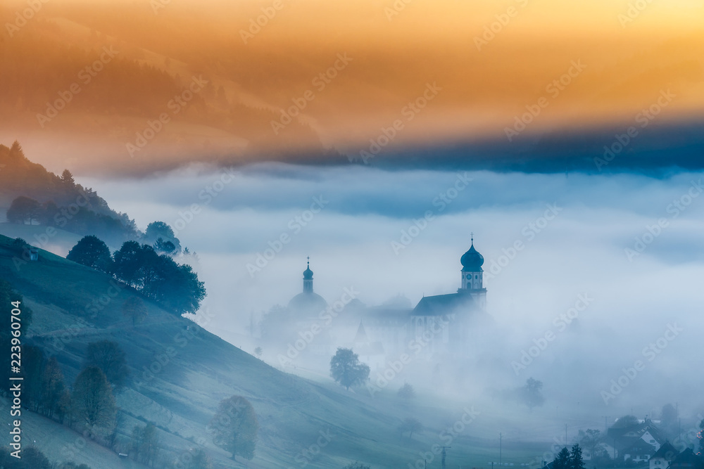 Obraz premium Malowniczy górski krajobraz ze starym klasztorem w Schwarzwaldzie w Niemczech, pokryty mgłą. Kolorowe tło podróży.