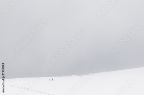 Wallpaper Mural A very minimalistic view of two distant people over a mountain covered by snow, near a fence Torontodigital.ca