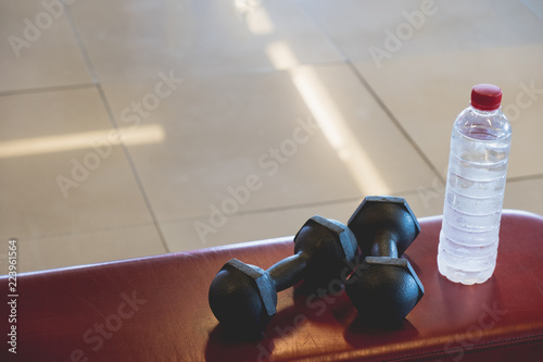 Dumbell and drinking water on red chair