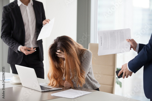 Depressed businesswoman feeling stressed bothered by male colleagues at work, female CEO suffer from headache or excessive workload annoyed by clients or subordinates, woman in despair manage anxiety photo