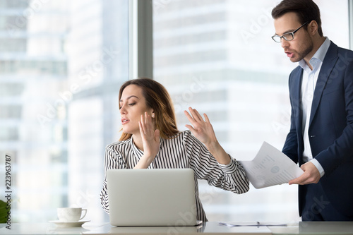 Tired bothered businesswoman abstracting from work refuse accept or consider report, annoyed female ceo gesturing rejecting mad business client or subordinate not looking at papers or documents photo