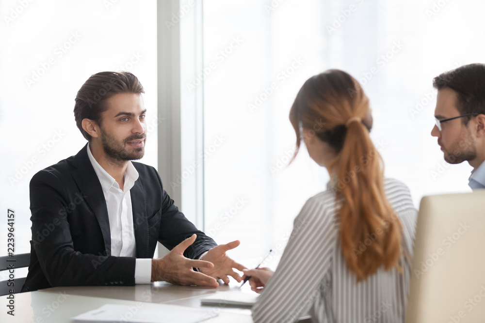 Confident millennial male job applicant talk at interview in office, HR team listen seriously to man employee at hiring process in boardroom, considering candidature. Recruitment, employment concept Confident millennial male job applicant talk at interview in office, HR team listen seriously to man employee at hiring process in boardroom, considering candidature. Recruitment, employment concept