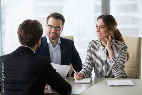 Smiling diverse HR managers satisfied about male job employee, have positive first impression of candidate, happy employers listen to applicant at interview excited of candidature. Recruitment concept photo