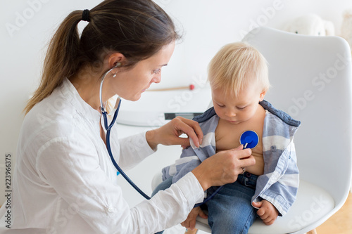 Pediatrician examining baby boy. Doctor using stethoscope to listen to kid photo