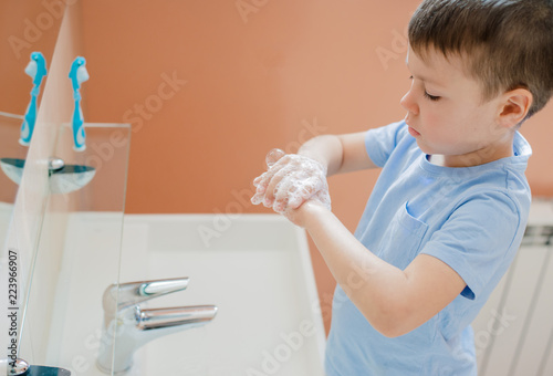 A little boy washes his hands with soap in the bathroom. The concept of cleanliness and hygiene.