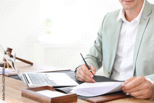 Male notary signing document at table in office  closeup