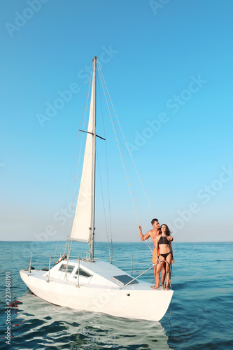 Young man and his beautiful girlfriend in bikini on yacht. Happy couple during sea trip