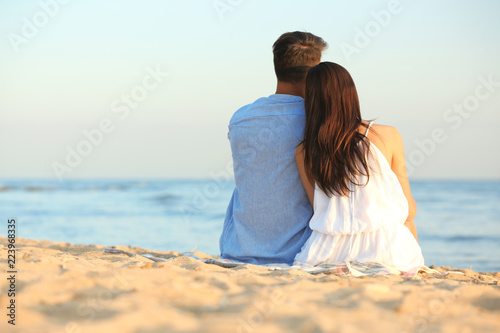 Happy young couple sitting together on beach