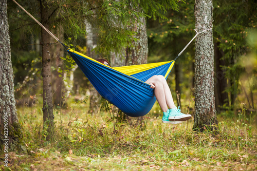 Image of brunette resting in hammock in forest