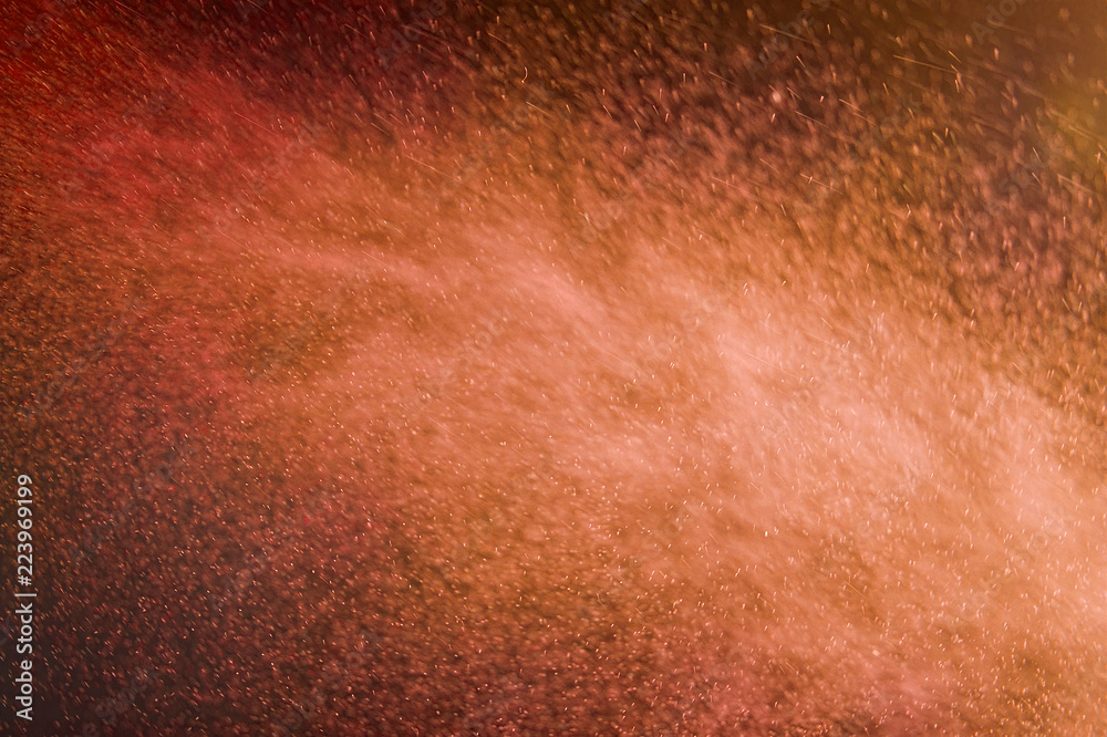ABSTRACT IMAGE OF RED AND ORANGE PARTICLES SWIRLING IN TURBULENT AIR