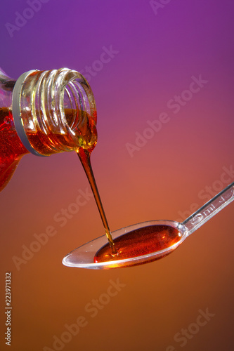 MEDICINE POURING FROM BOTTLE INTO PLASTIC SPOON