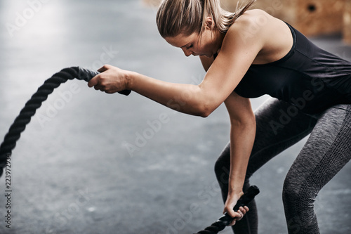 Canvas Print Fit young woman swinging ropes during a gym workout