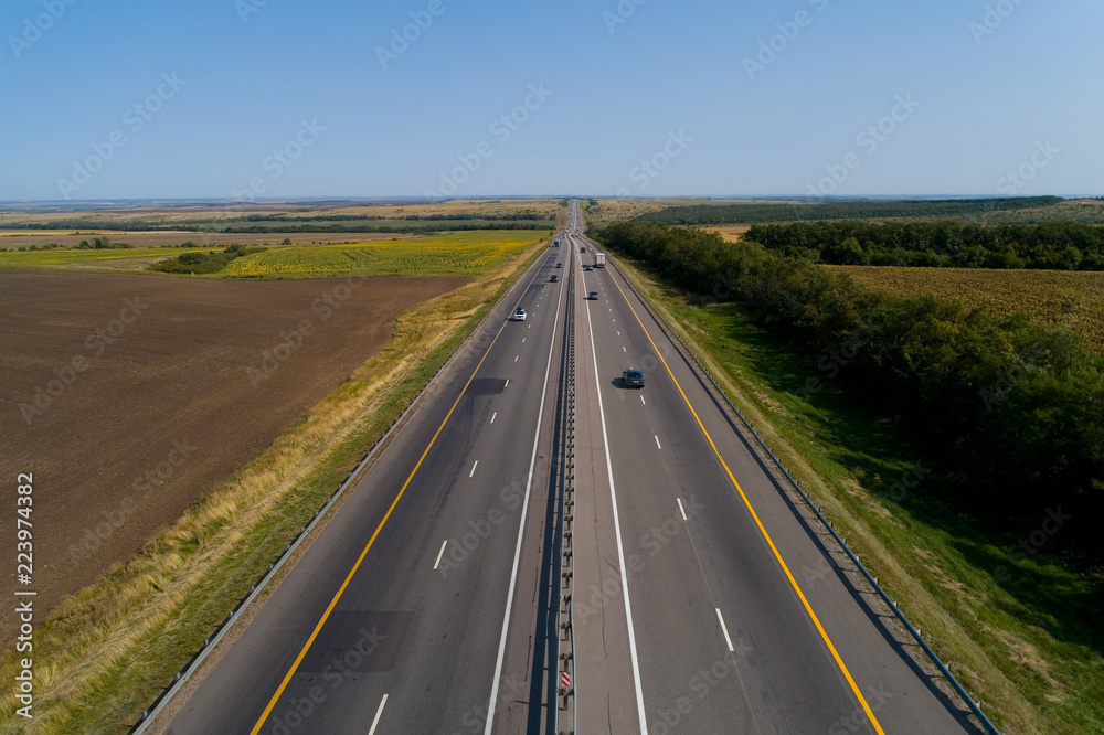 Cars drive on the highway outside the city on a cloudless day.