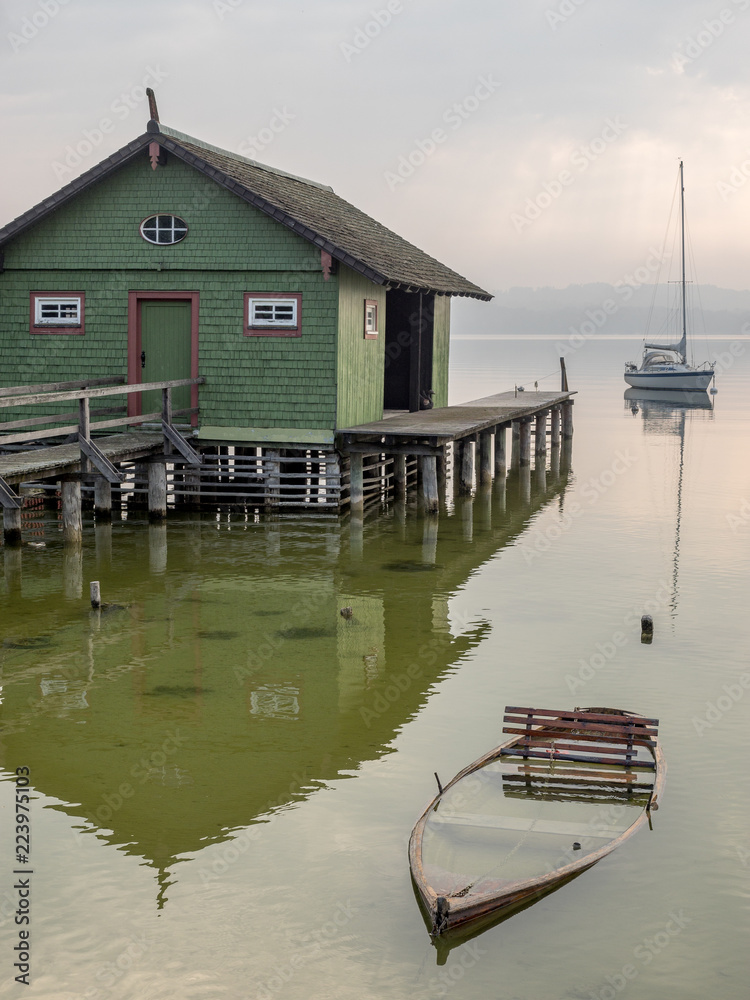 Grünes Bootshaus mit untergegangenem Ruderboot am Ammersee