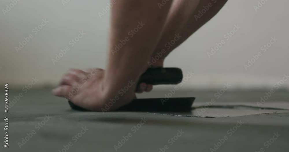 Slow motion closeup male worker applying micro concrete on the floor with a trowel
