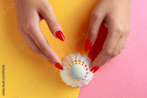 Fun minimal concept. Woman hands with badminton shuttlecock. Top view. Pastel colours background. Trendy colors.