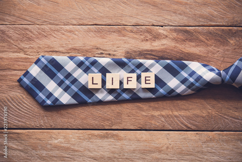 Necktie and the message "Life" put on wooden floor - Concept of life.