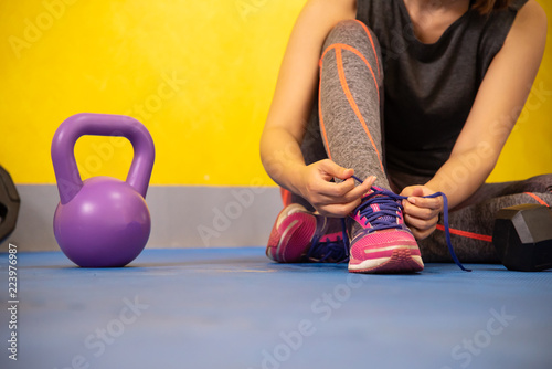 The hands of a girl's shoelace and sneakers in the gym are ready to exercise.